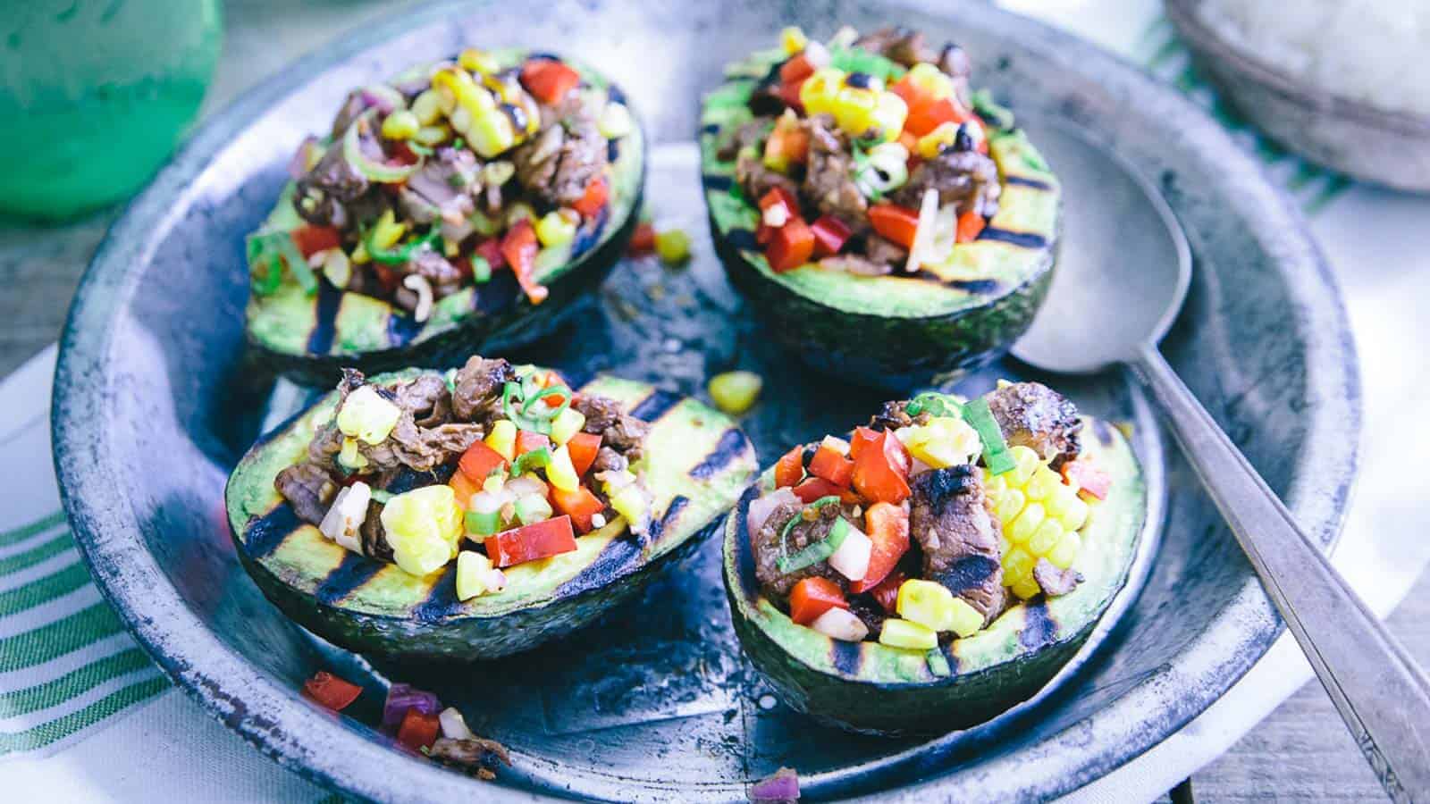 Steak stuffed grilled avocados on a metal plate.