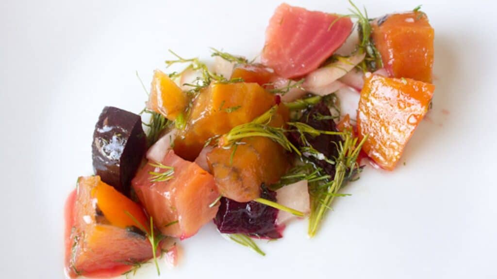 Assorted cubed beetroot and salmon salad garnished with dill.