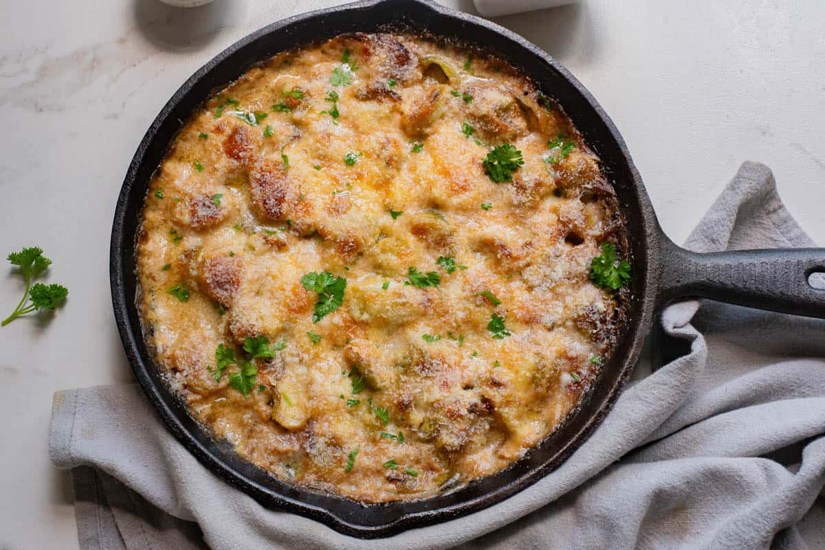 Brussels sprouts in a cast iron pan with golden brown cheese topping.