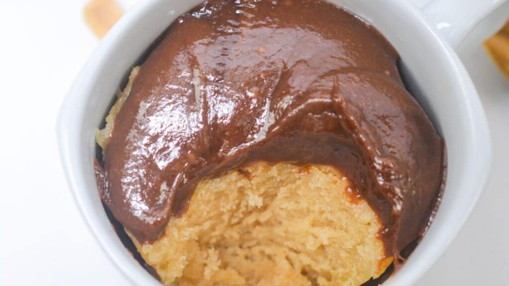 A peanut butter mug cake topped with a thick layer of glossy chocolate sauce, viewed from above.