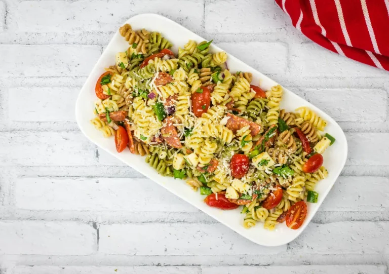 A platter of pizza pasta salad served on a white rectangular dish.