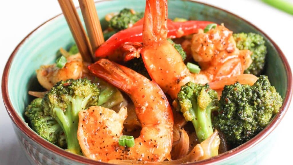 Stir-fried shrimp and broccoli in a bowl with chopsticks.