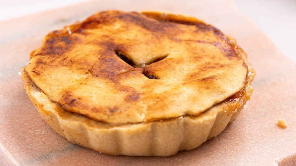 Close-up of a freshly baked apple pie with a golden-brown crust and a visible vent hole on top.