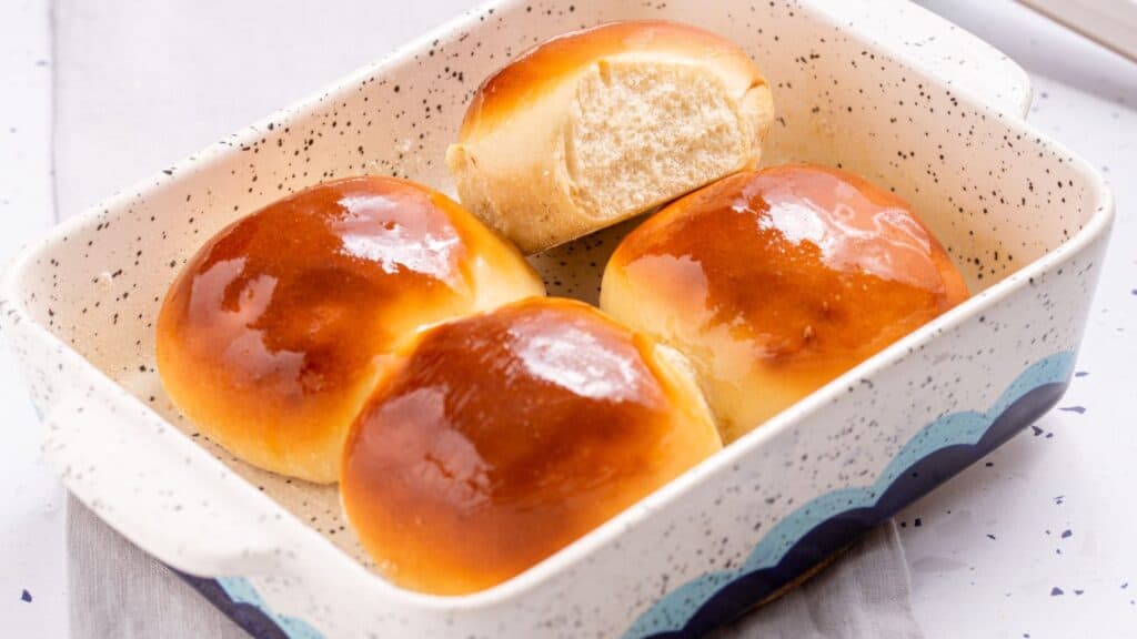 Freshly baked rolls with a glossy top in a ceramic dish.