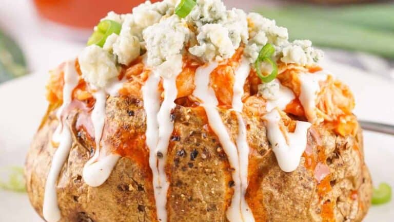 A loaded baked potato topped with buffalo chicken, blue cheese crumbles, and drizzled with ranch dressing.