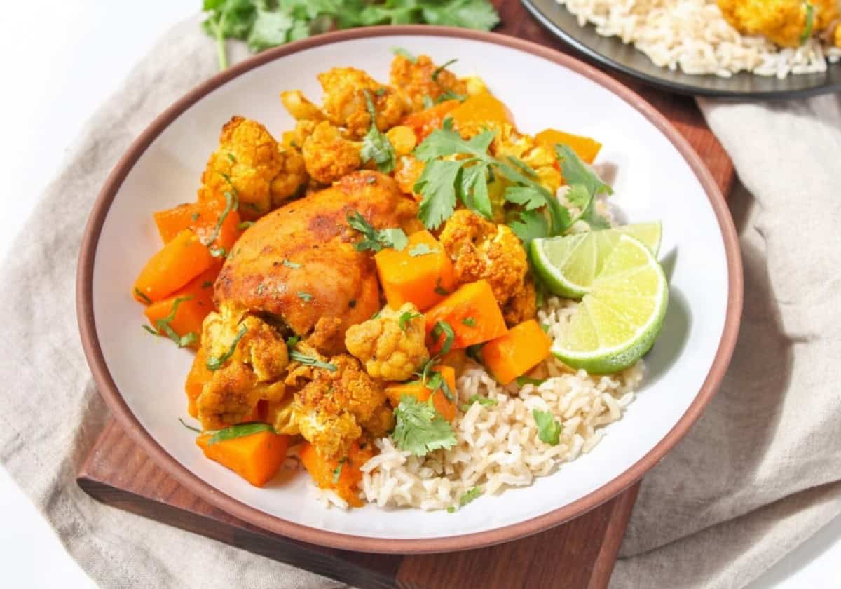 Roasted chicken thighs with butternut squash, cauliflower, and rice on a plate.