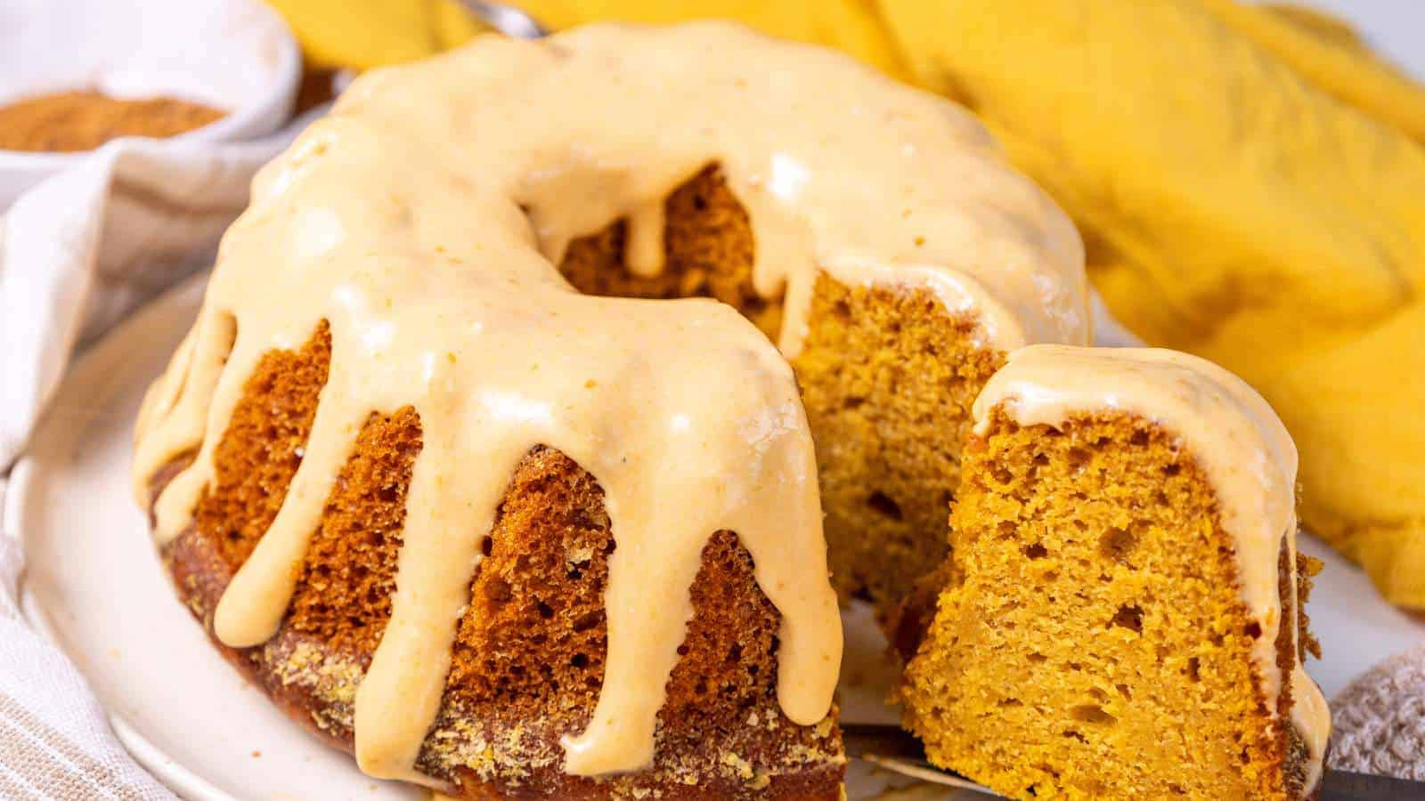 A pumpkin bundt cake with vanilla glaze on a white plate.