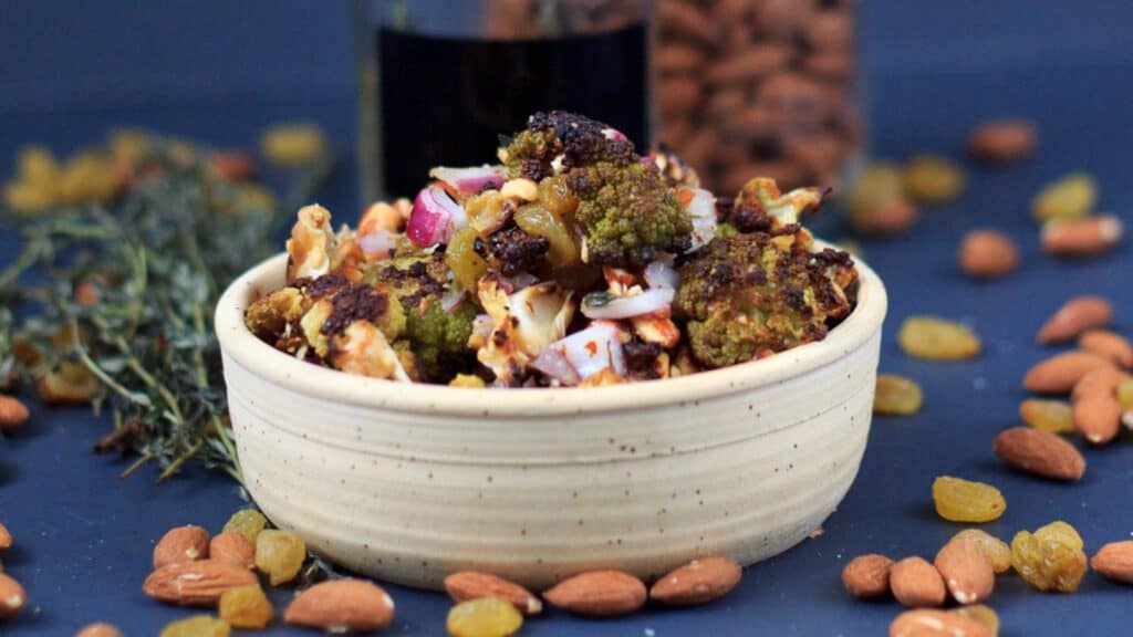 A bowl of roasted cauliflower with onions and sprigs of thyme.