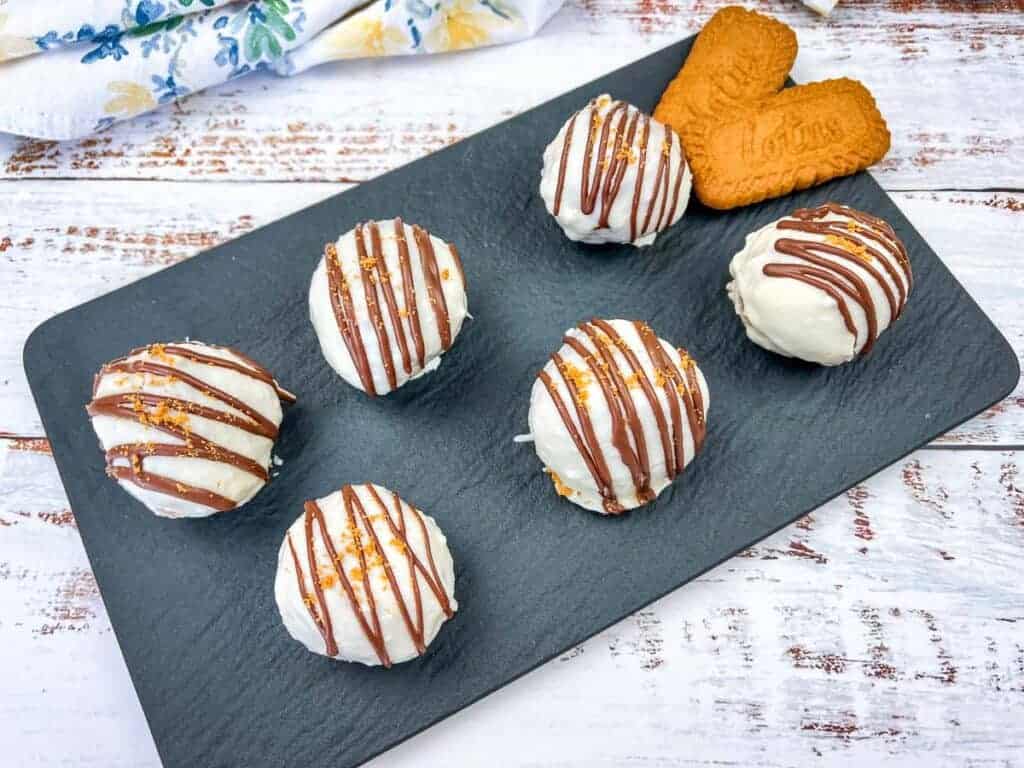 Six Biscoff Cookie Butter Cake Balls arranged on a black slate serving tray.