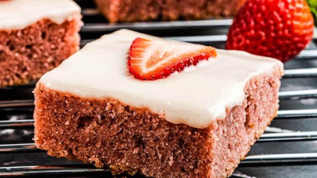 Close up on a brownie with glaze and strawberries.