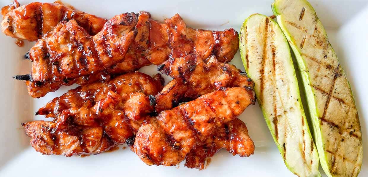 Grilled bbq chicken and zucchini on a platter.