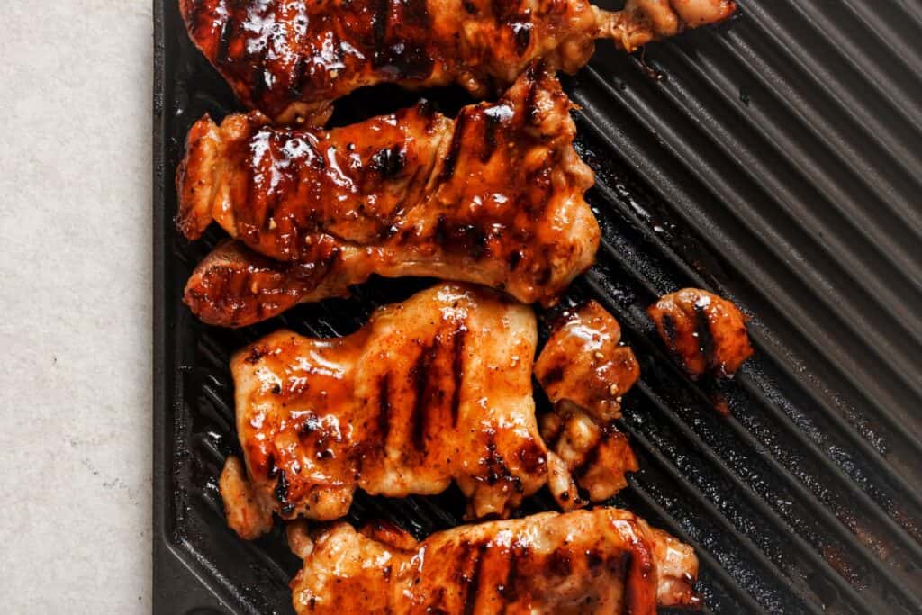 Grilled and glazed pieces of meat on a ridged grill pan.