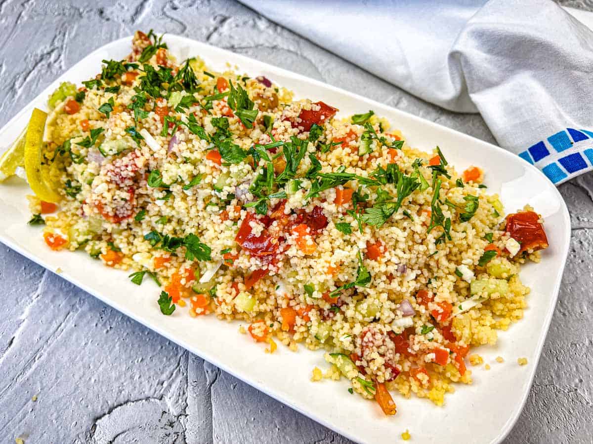 A plate of Mediterranean Couscous Salad With Smoked Tomatoes topped with parsley.