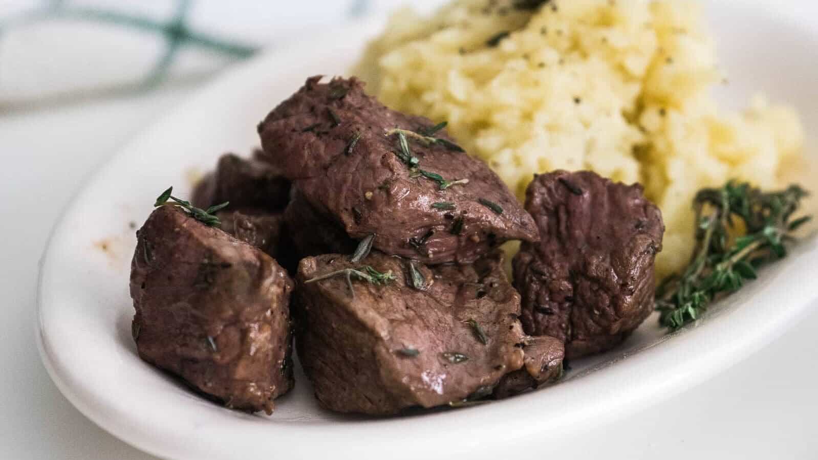 Air fried steak bites on a white plate.