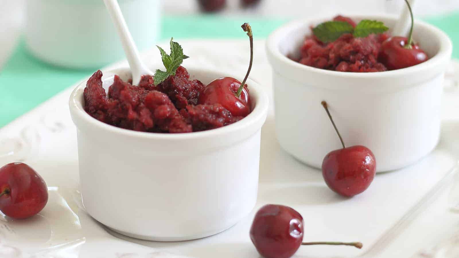 Cherry lemon granita in small white ramekins garnished with mint leaves.