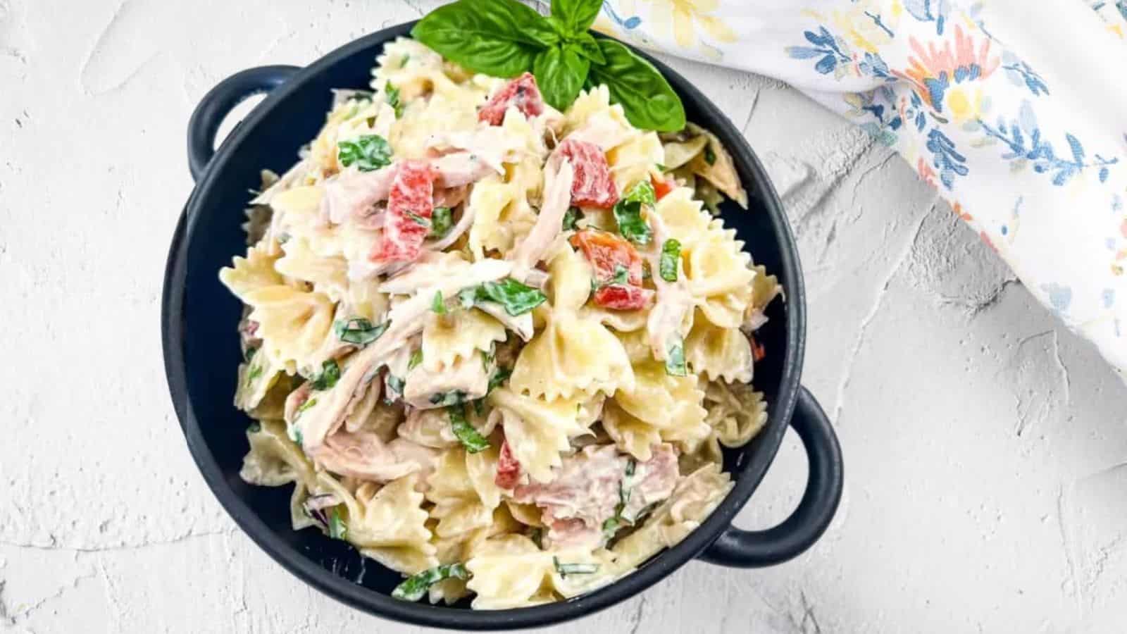 A black bowl filled with rotisserie chicken pasta salad.