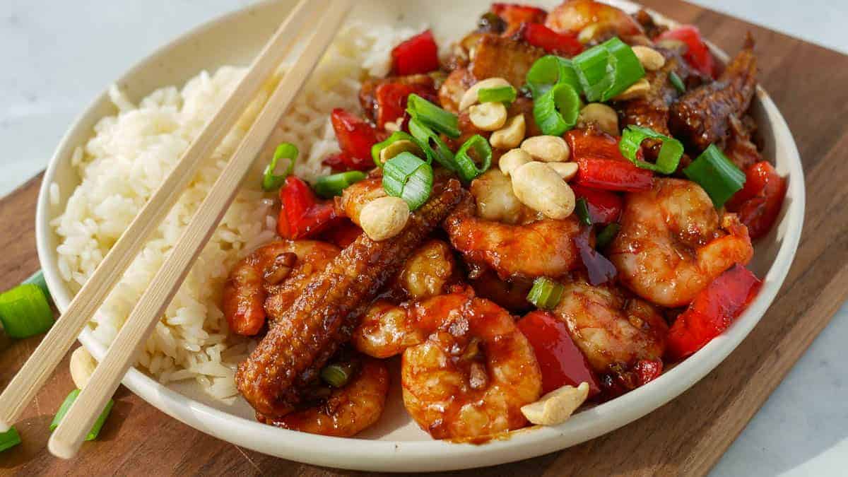 A plate of stir-fried shrimp and vegetables with cashew nuts served over rice.