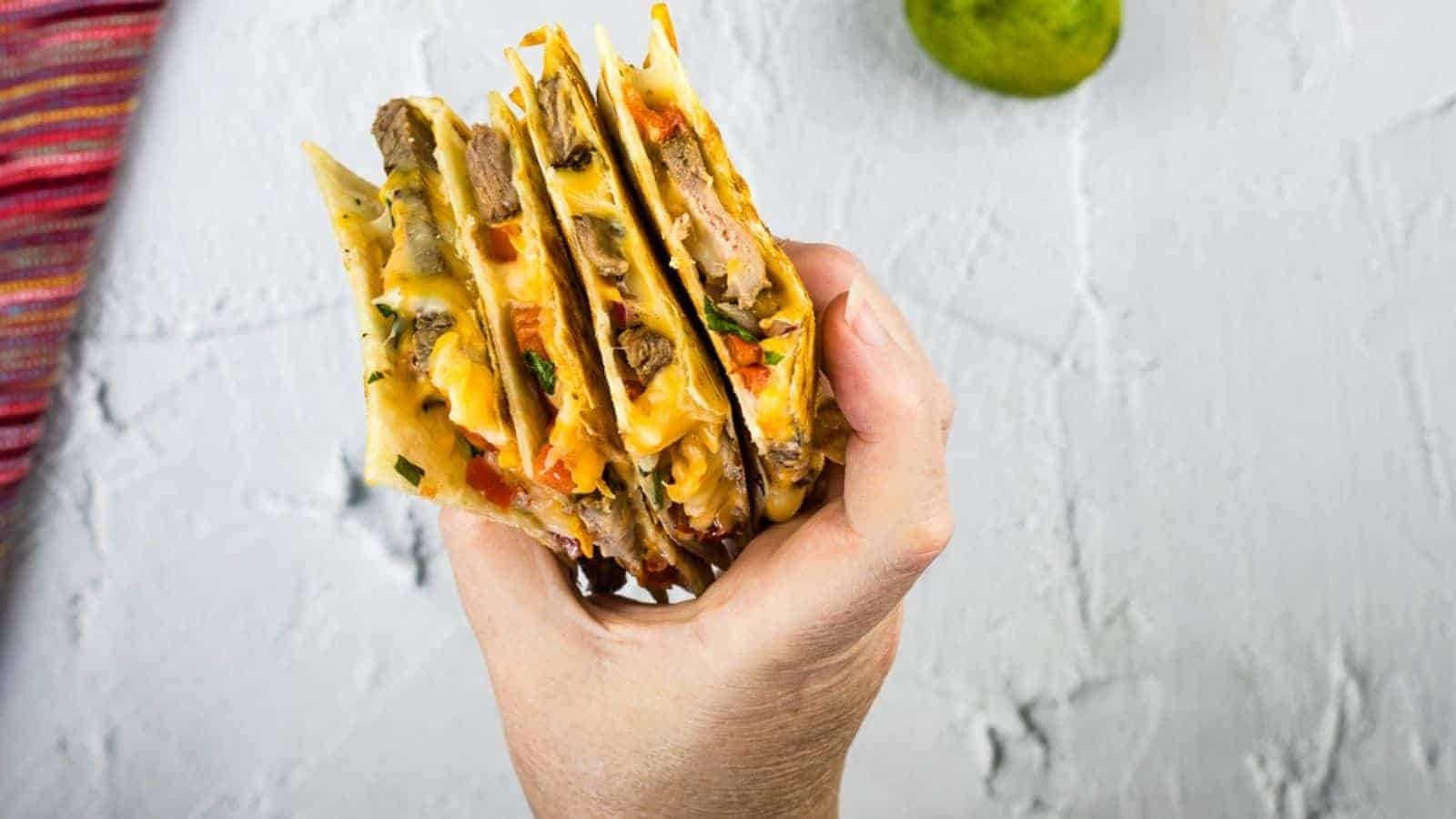 A hand holding wedges of a quesadilla.