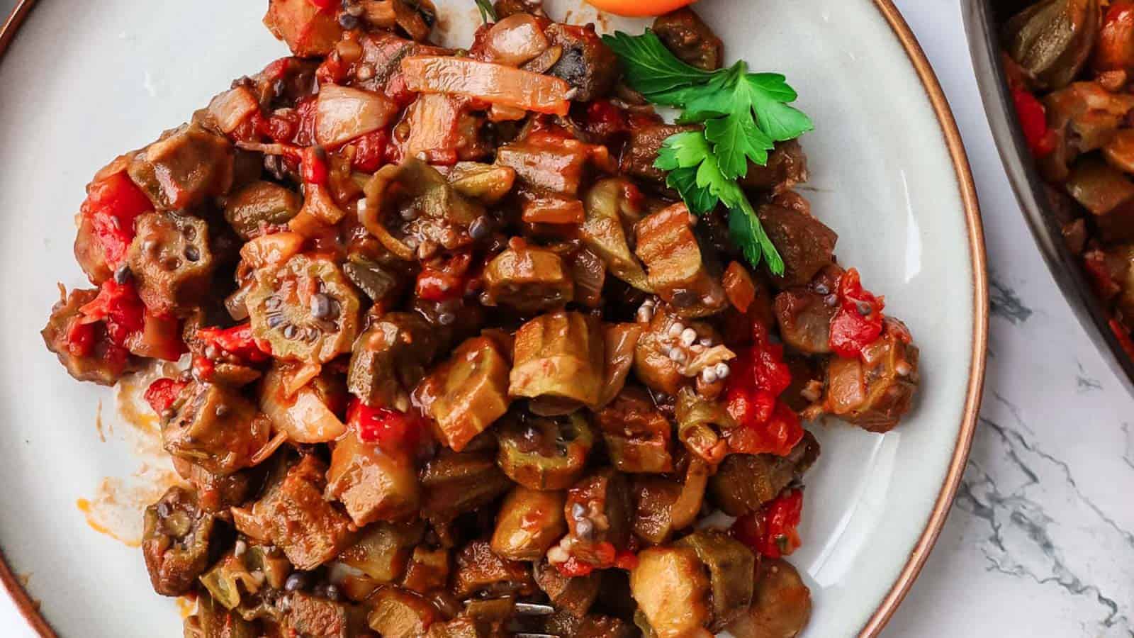 Stewed okra and tomatoes on a plate with parsley garnish.