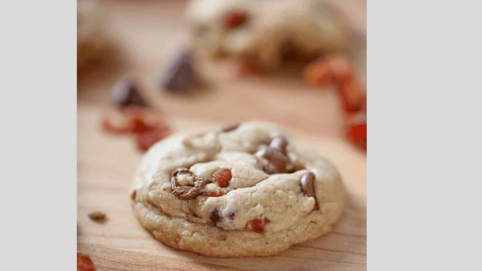 A cookie with bacon and chocolate chips on a wooden surface.