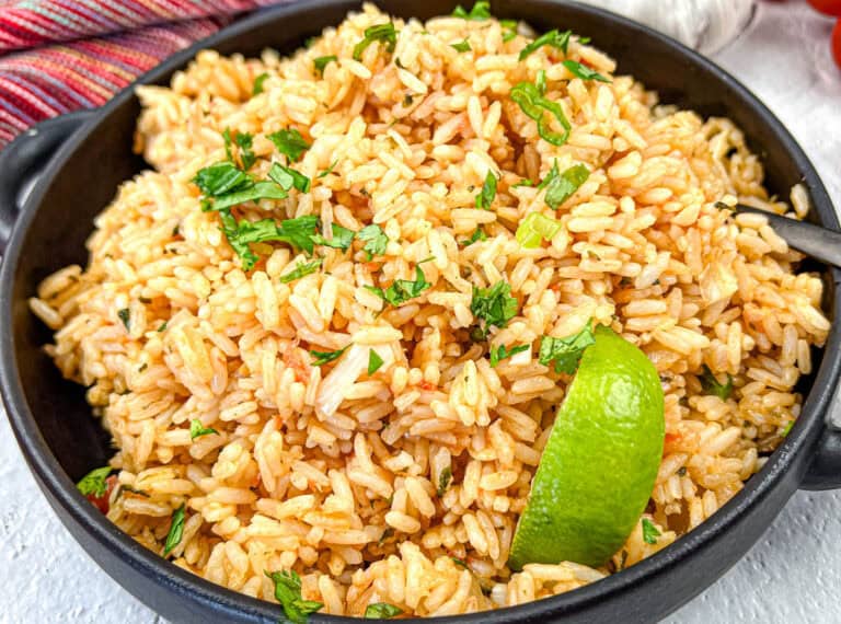 Mexican Rice with a slice of lime on a black bowl.