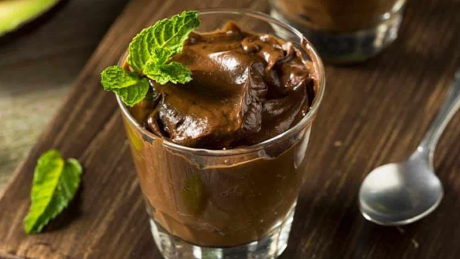 Chocolate avocado pudding in glass with spoon.