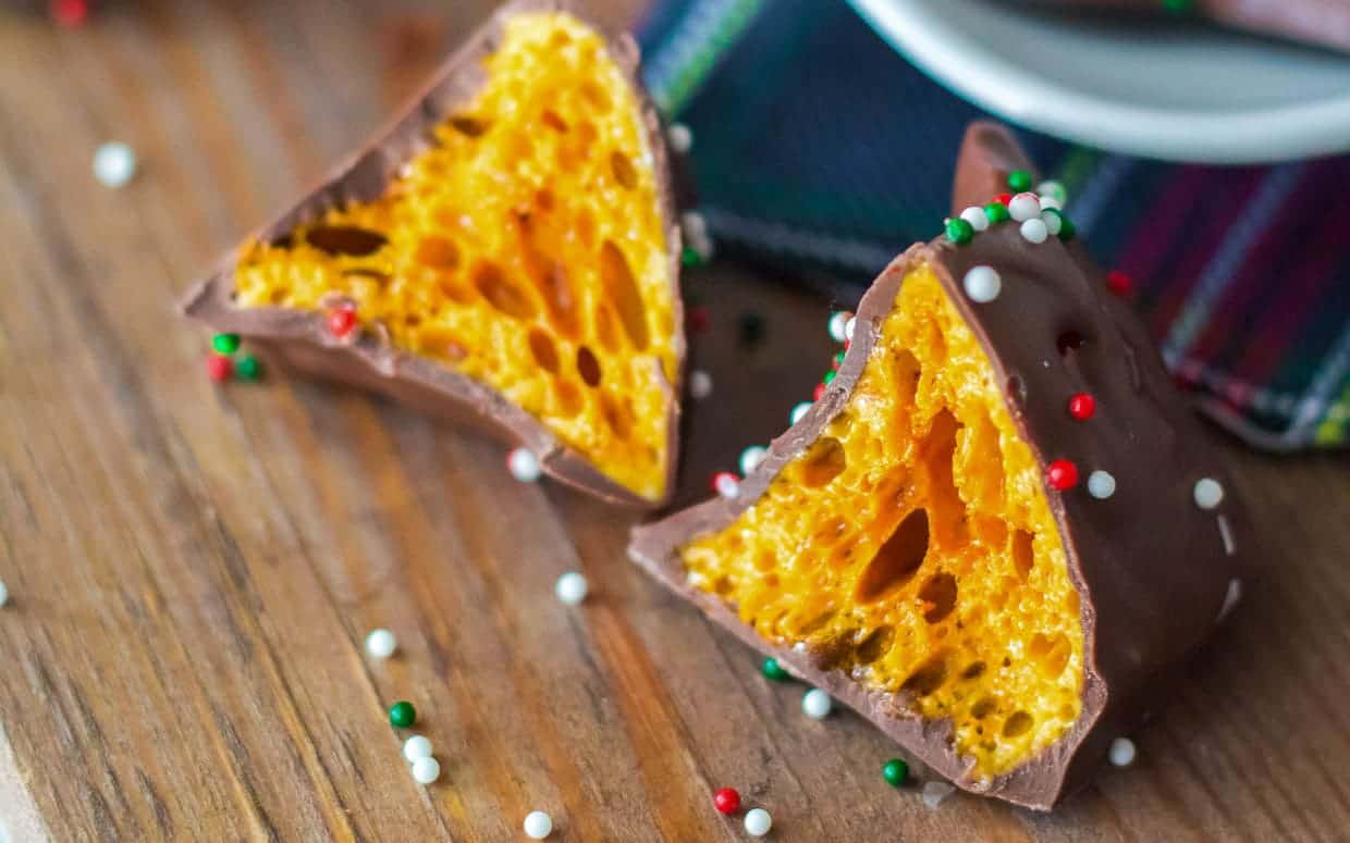 A piece of chocolate covered candy is sitting on top of a wooden table.