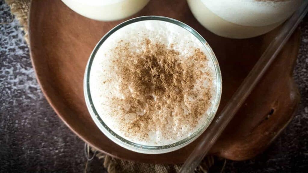 Three glasses of dIrty chai smoothie on brown tray with glass straw.