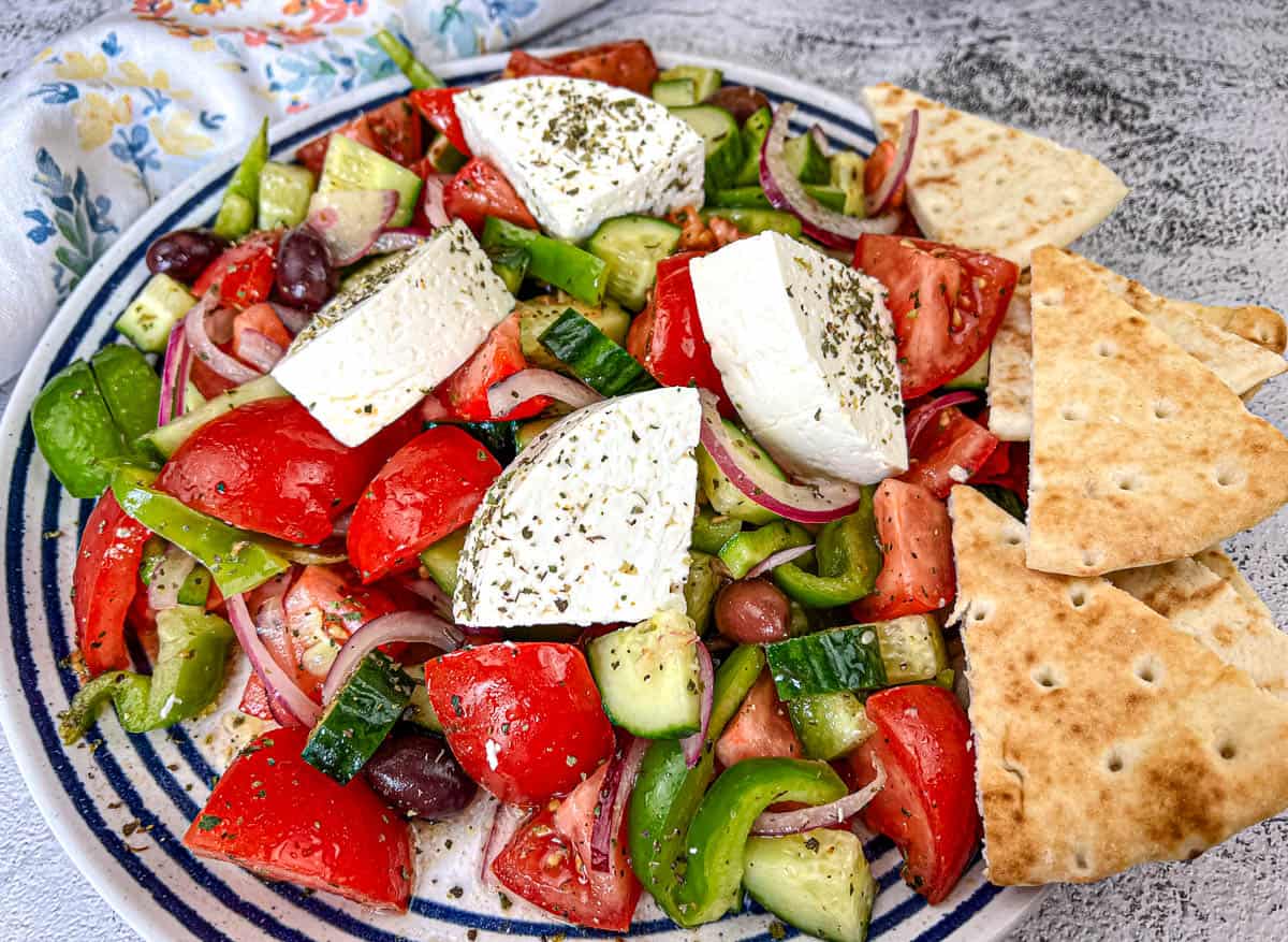 Horiatiki Salad with feta cheese on top served on a plate.