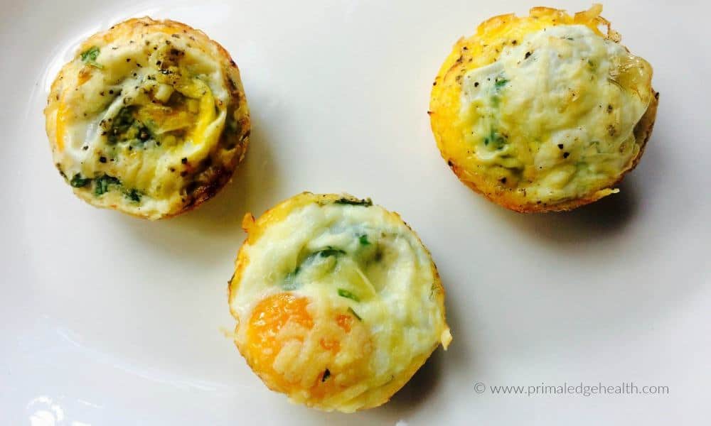 Three egg muffins with visible herbs and cheese on a white plate.