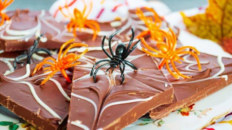 Chocolate bark decorated with orange and black plastic spider toys.