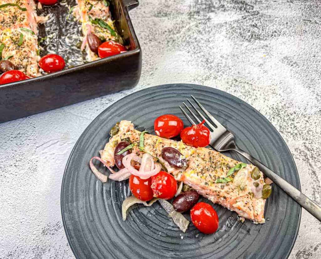 A plate of Greek salmon with grape tomatoes and olives.