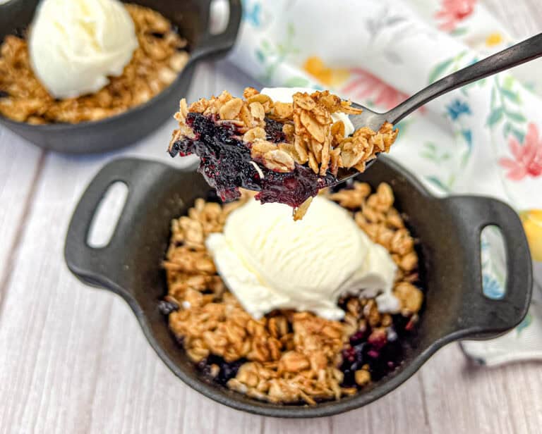 A spoon lifts a portion of Smoked Berry Crisp from a bowl.