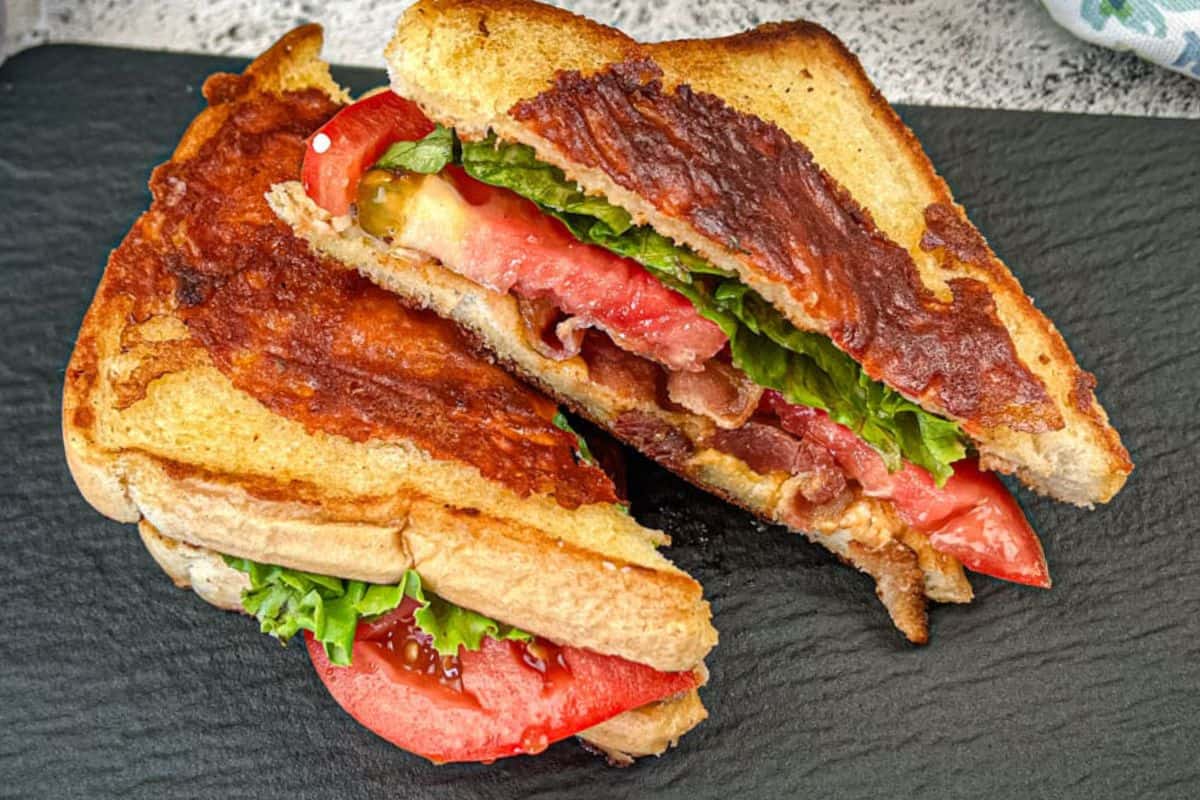 Two halves of Texas BLT on a black plate.