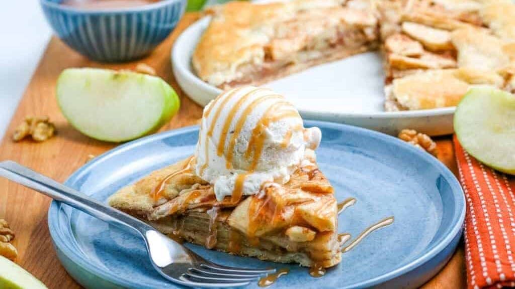 A slice of apple pie with ice cream on a plate.