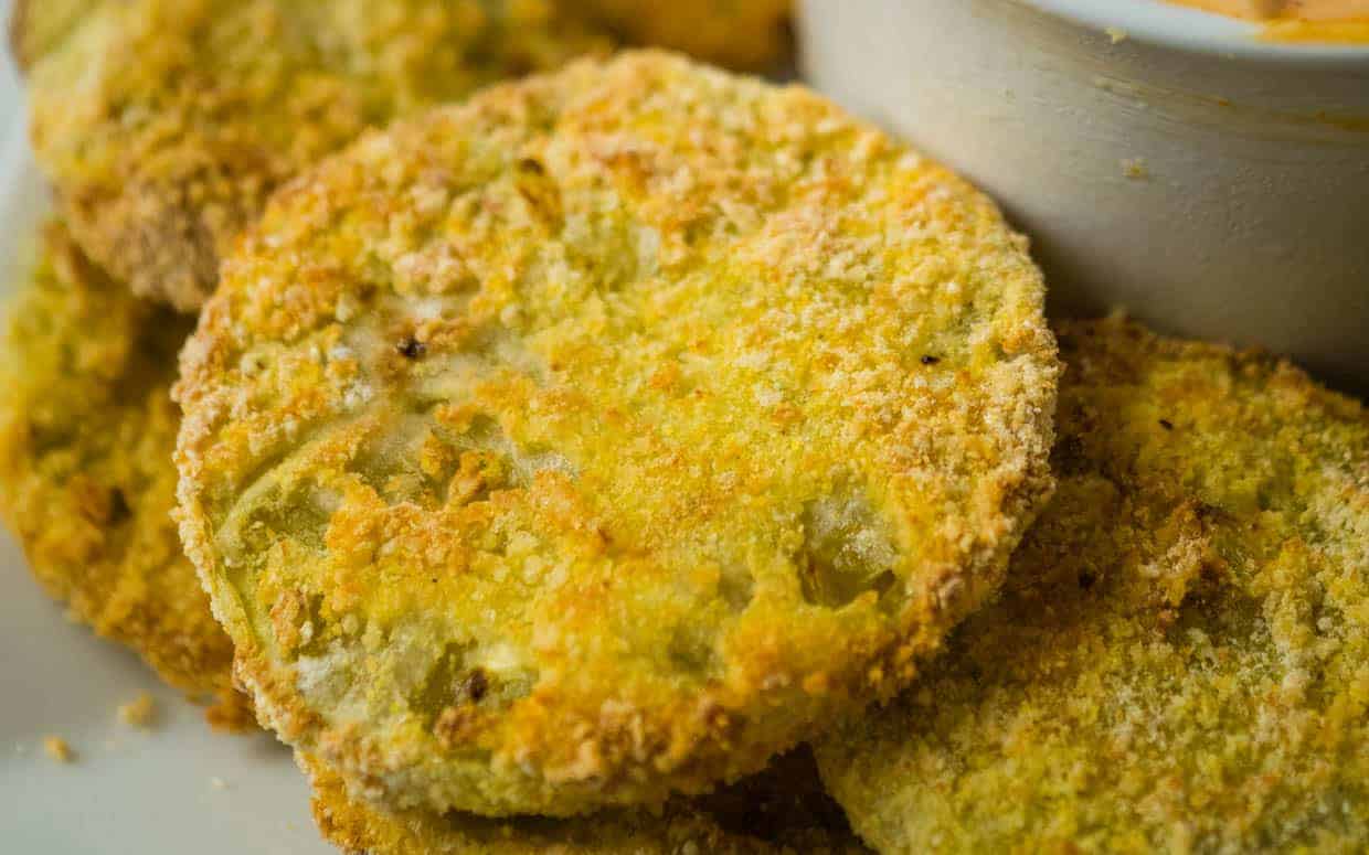 Closeup of a pile of fried green tomatoes on a plate.