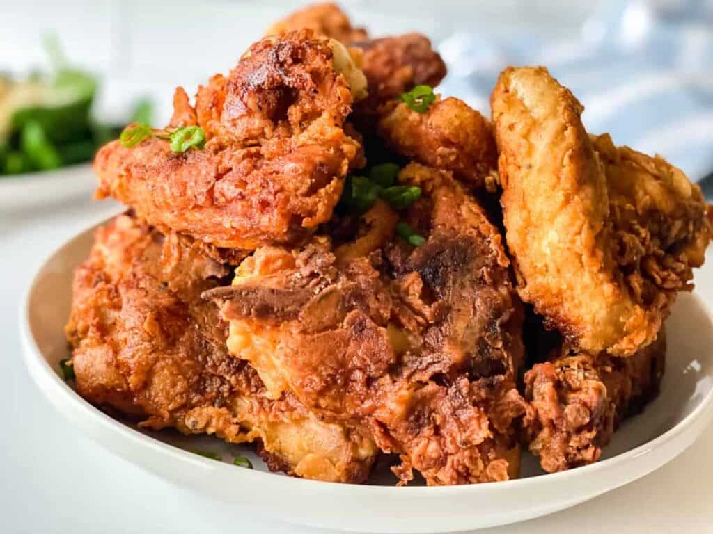 A plate of crispy fried chicken pieces garnished with chopped green onions.