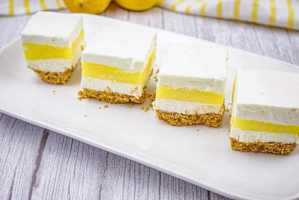 Four pieces of lemon lush on a white plate.