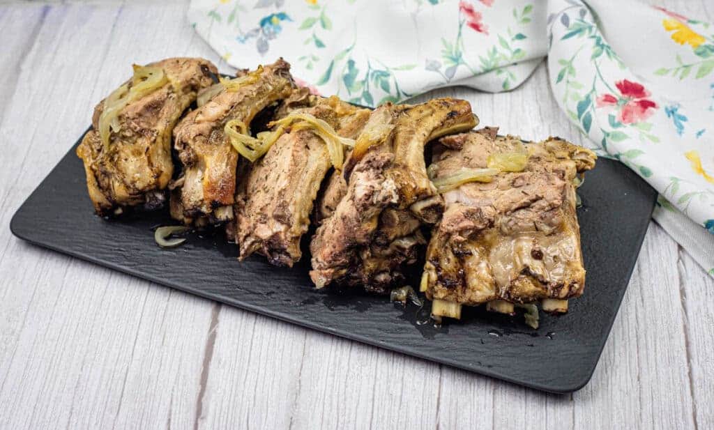 Pieces of oven bake ribs on a black slate plate.