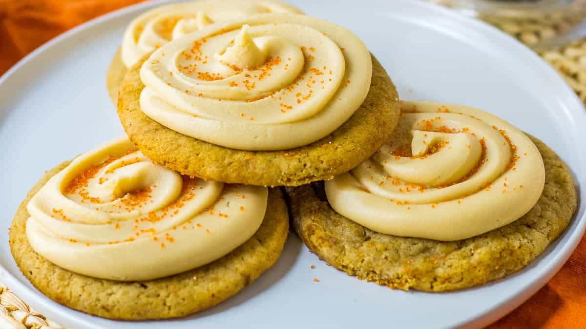  A caramel apple cookie with thick, swirled frosting, presented on a white plate.