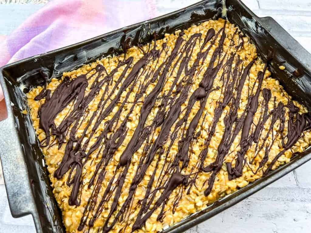 A rectangular baking pan filled with molly bars and melted chocolate drizzle.