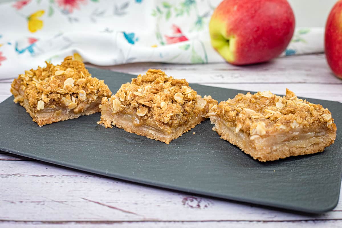 Three pieces of Dutch Apple Pie Squares on a black slate plate.